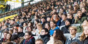 Studierende des ersten Semesters sitzen bei der Erstsemesterbegrüßung auf den Rängen im Stadium.